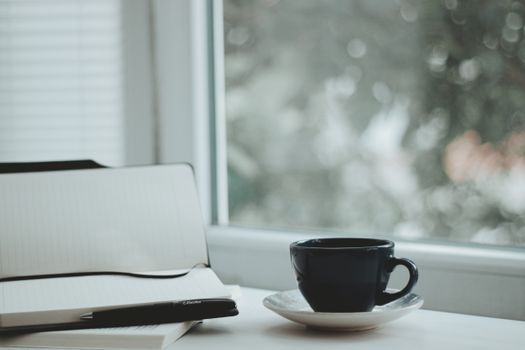 Woman writing in a travel notebook beside a coffee cup near a hotel window