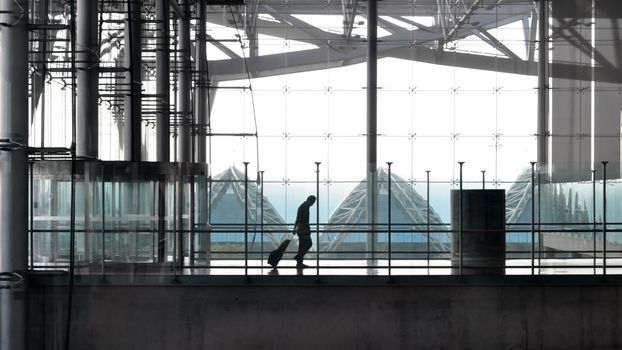 Traveler pulling a suitcase through a bright airport terminal