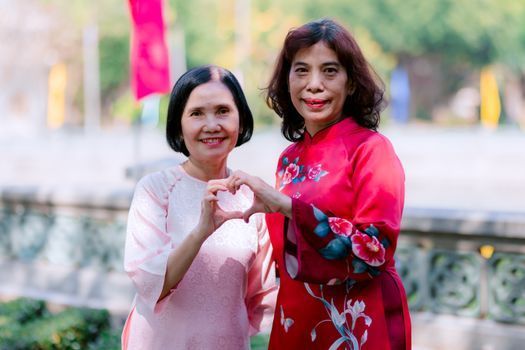 Two women of different ages smiling together outdoors in natural light