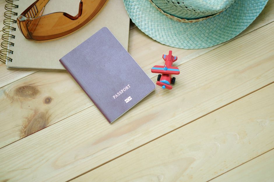 Passport, sunglasses and a tube of sunscreen laid out on a table