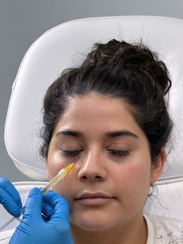 Close-up of a fine-needle skin booster injection on a woman's cheek