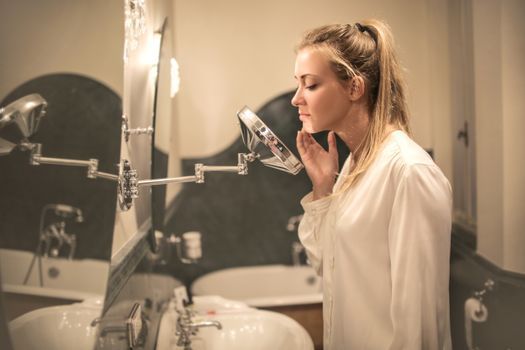 Young woman examining the skin on her cheek in a mirror