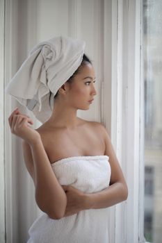 Woman with soft, natural facial contours looking out of a window in daylight