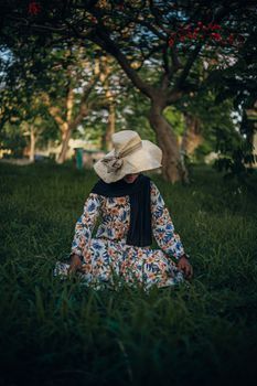 Woman in a wide-brimmed hat walking through a shaded palace garden