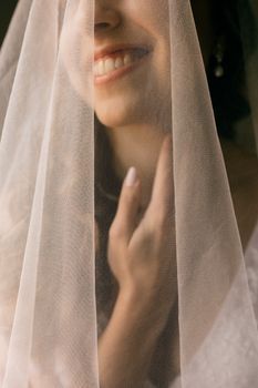 Smiling bride touching her cheek in soft window light