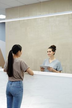 A patient checking in at the reception desk of a bright, modern skin clinic