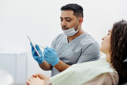 Doctor discussing facial contours with a patient holding a hand mirror