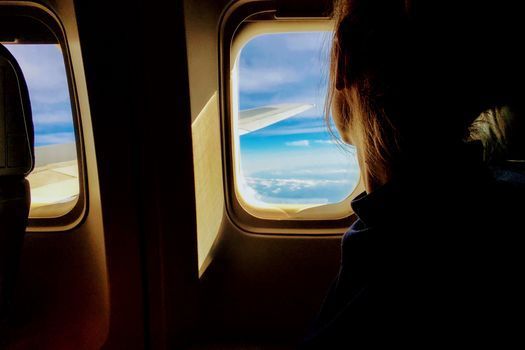 Woman relaxing by an airplane window during a daytime flight