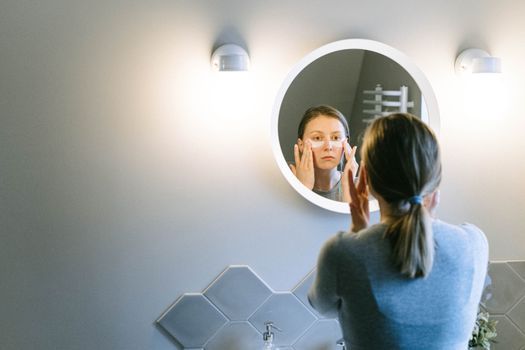 Woman holding a cool compress under her eyes