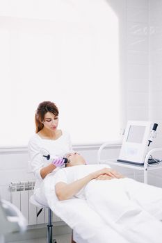 Woman with fresh, glowing skin sitting in a bright clinic after a laser facial treatment