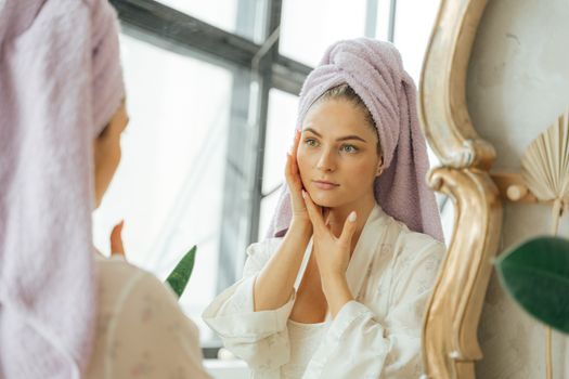 Woman touching her cheek in a bright bathroom