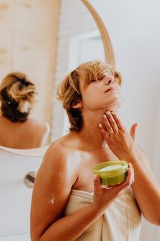 Woman applying moisturizer to her neck