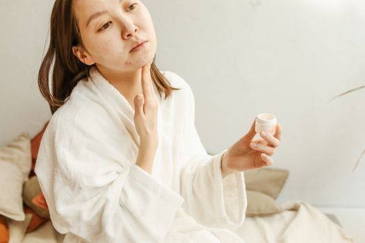 Woman gently applying a soothing cream to her cheeks