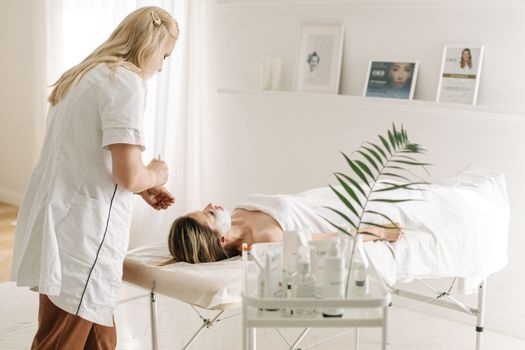 Calming mask being placed on a woman's face after a skin treatment