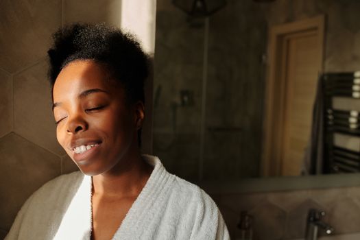 Woman with glowing skin smiling in warm morning sunlight
