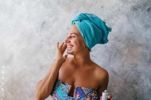Woman applying sunscreen to her cheek in a bright bathroom