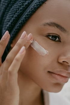 Woman applying sunscreen to her cheek outdoors