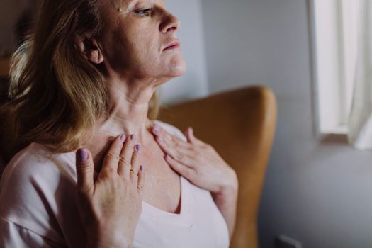 Mature woman touching her neck in soft natural light