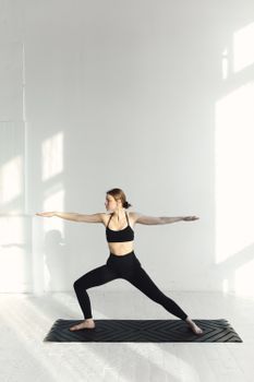 Woman in activewear stretching in a bright studio