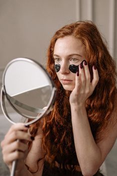 Woman examining the area under her eyes in a mirror