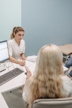 Doctor talking with a patient across a desk in a modern clinic consultation room