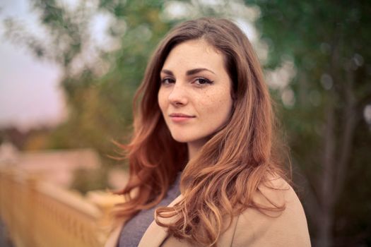 Young woman with freckles smiling outdoors