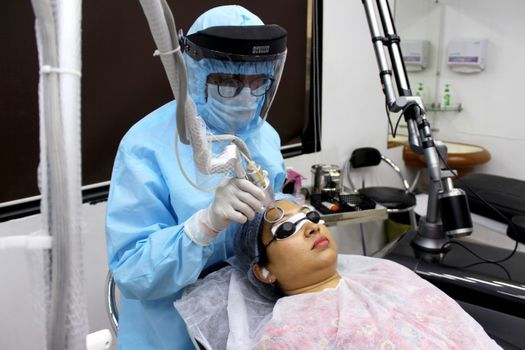 Doctor using a fractional laser handpiece on a patient’s cheek