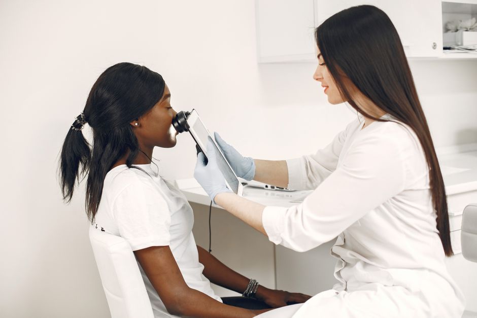Dermatologist closely examining a woman's facial skin during an assessment