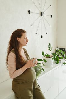 Pregnant woman relaxing on a sofa with a cup of tea at home