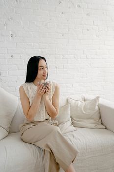 Woman resting on a sofa with a cup of tea in a calm apartment