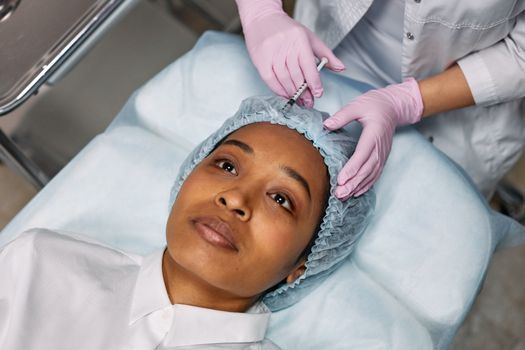 Doctor giving a small injection in a woman's forehead to soften expression lines