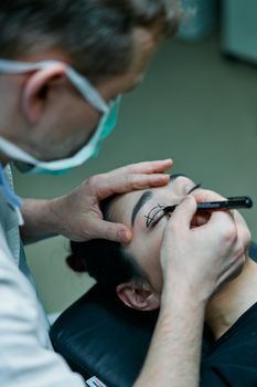 Doctor marking planned treatment points on a woman's cheek before a lifting procedure
