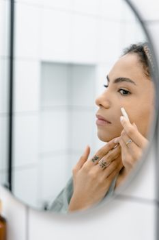 Woman with dewy, hydrated skin looking at her reflection in a mirror