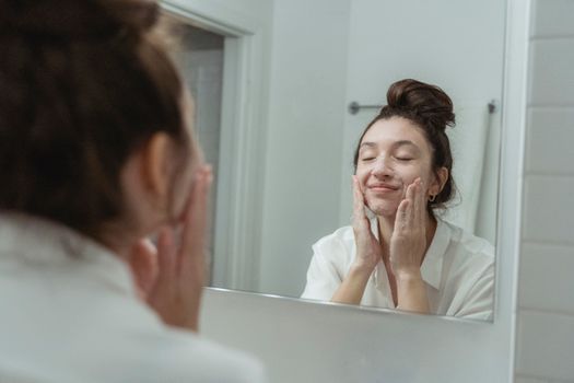 Young woman washing her face with a gentle cleanser at a sink