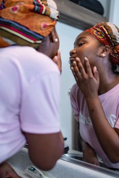 Young woman checking her jawline in a mirror in daylight
