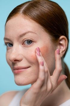 Woman gently touching her cheek in soft daylight
