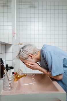 Young man washing his face at a bathroom sink