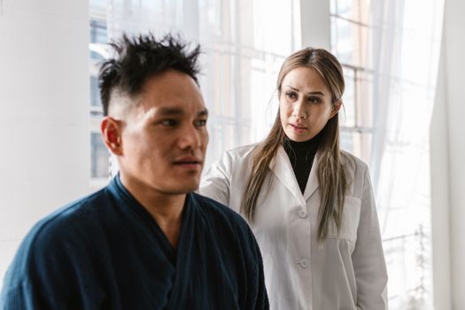 Doctor assessing skin firmness along a woman's jawline during a consultation