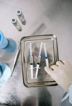 Doctor preparing an injectable vial and syringe on a clinic tray
