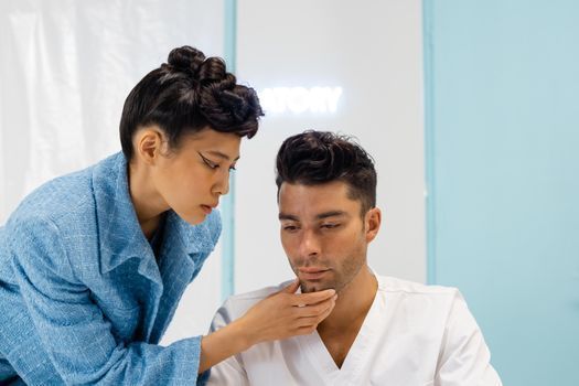 Doctor assessing the cheek contour of a woman in a bright clinic