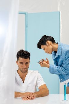 Doctor giving an injection into the jaw muscle of a young woman
