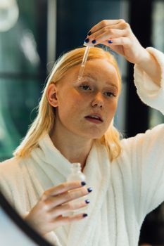Woman applying a hydrating serum with a dropper