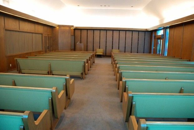 Empty church interior with wooden pews and teal seats facing the front