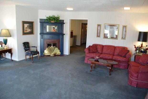 Spacious living room with blue carpet, red sofa, fireplace, and wall art.