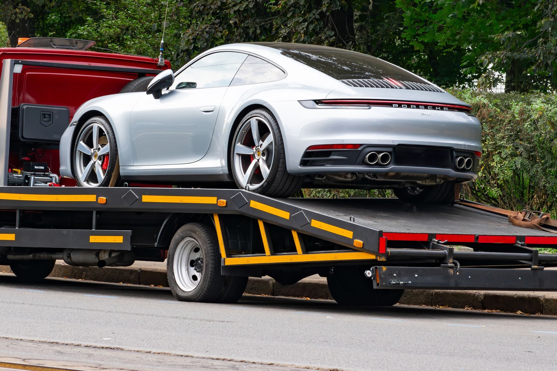 Silver sports car on a flatbed tow truck on a roadside
