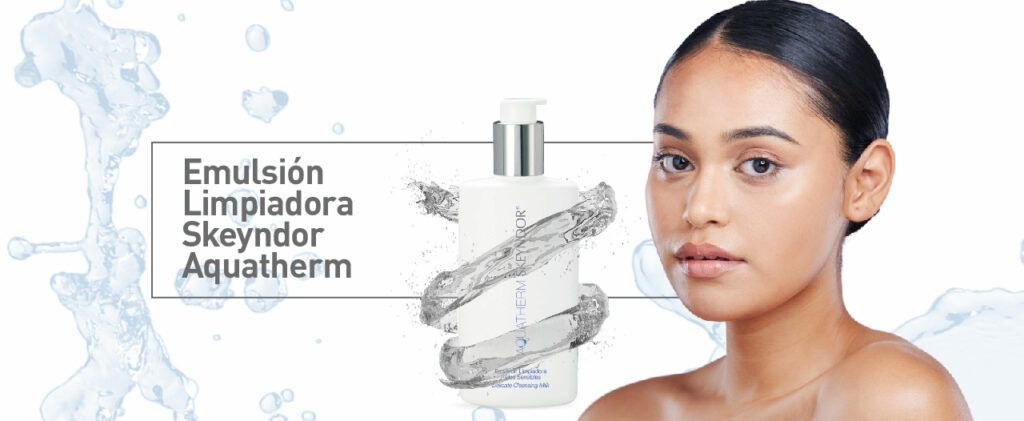 Una mujer está parada frente a una botella de emulsión limpiadora skeyndor aquatherm.
