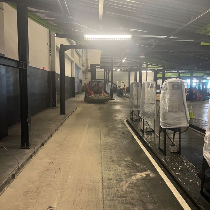 Indoor warehouse aisle with a forklift in the distance and covered equipment along the right side.