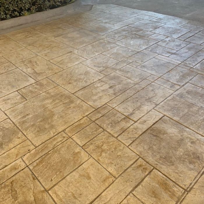 Stamped concrete patio with tan, stone-patterned tiles in daylight