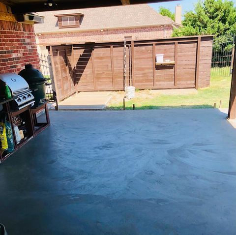 Backyard patio with a grill, wooden shed, and sunlit concrete ground