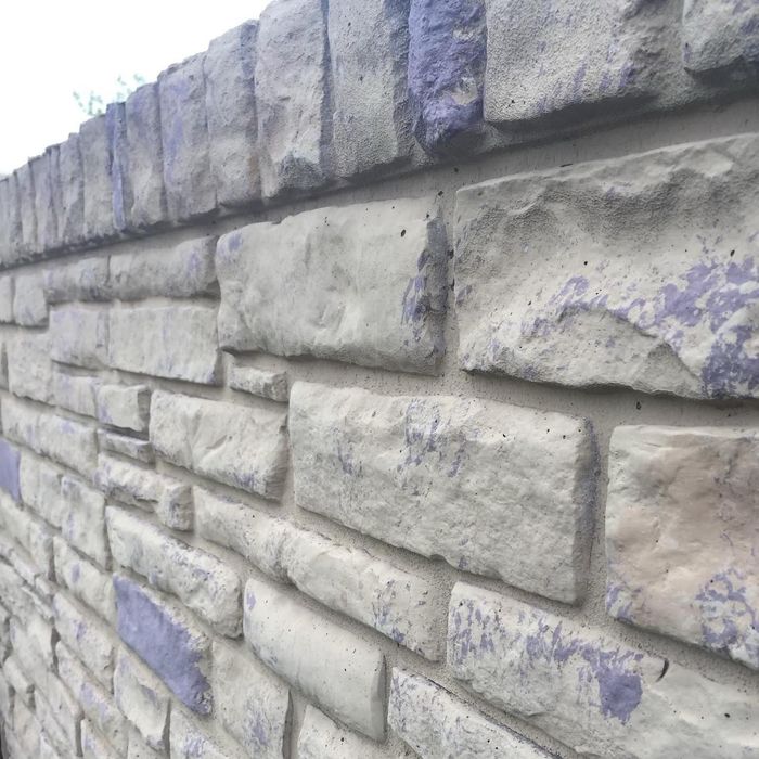 Close-up of a gray stone wall with stacked blocks and purple paint marks